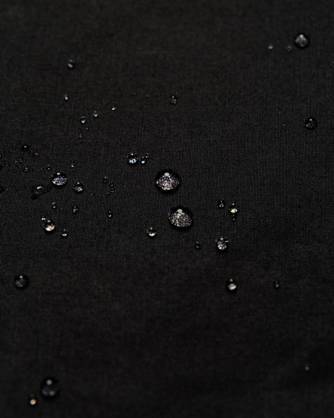 Roam Raglan Jacket - Black — water beading proves weatherproofing